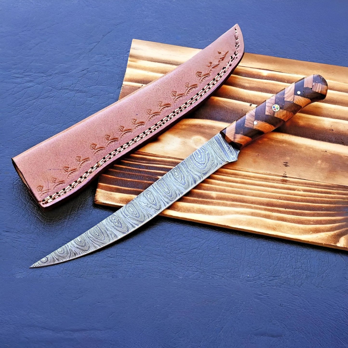 Damascus fillet knife with leather sheath on wooden board