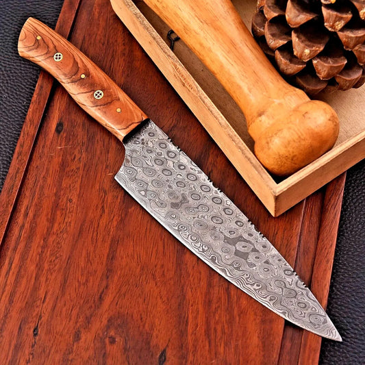 7 inch hand forged Damascus chef knife with raindrop pattern blade and olive wood handle on wooden board